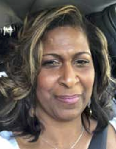 Close-up portrait of Tia Farmer with shoulder-length curly hair, seated in a car.